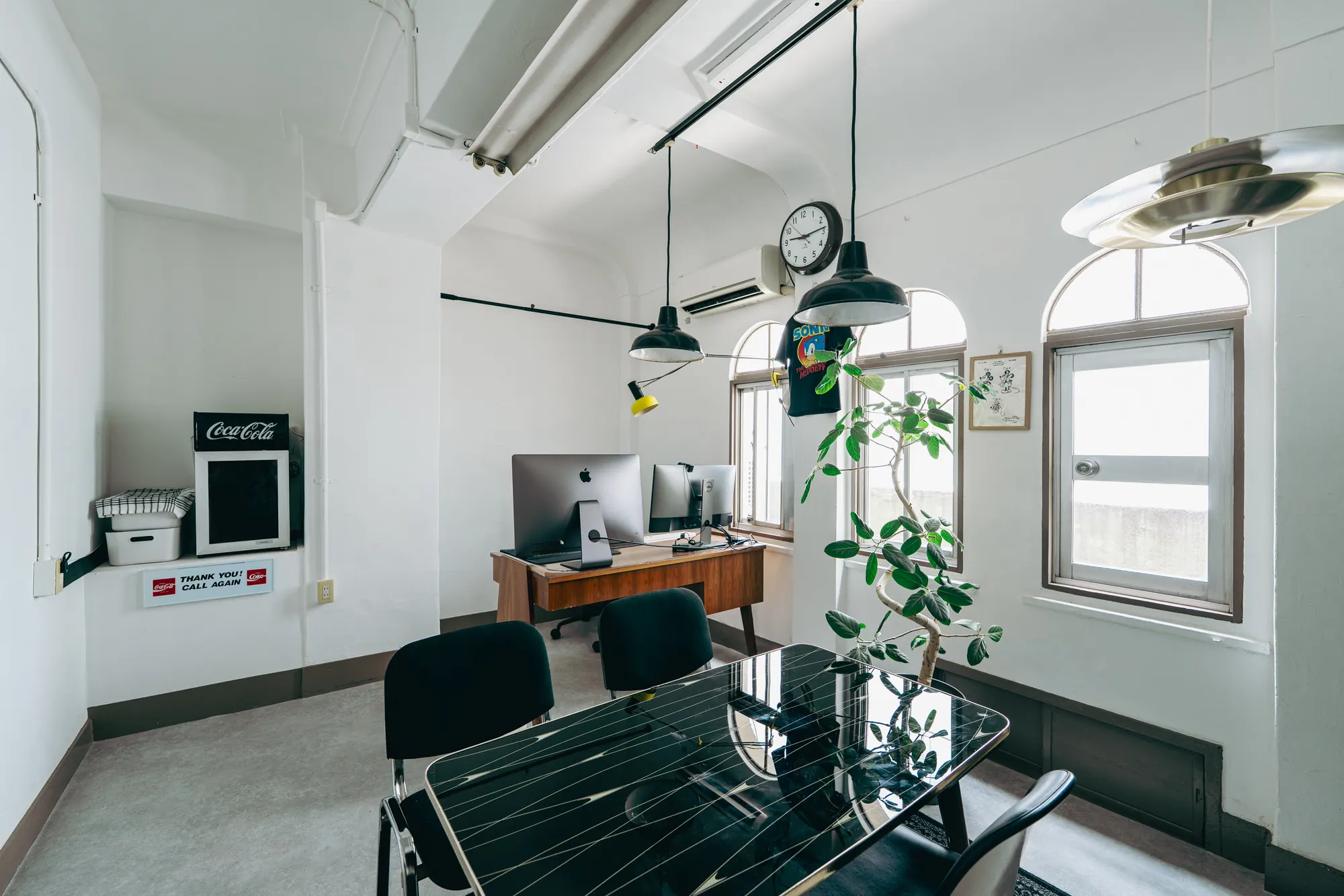 デスクに並んだMacと、手前のテーブル。仕事をする道具が置かれた部屋の一角