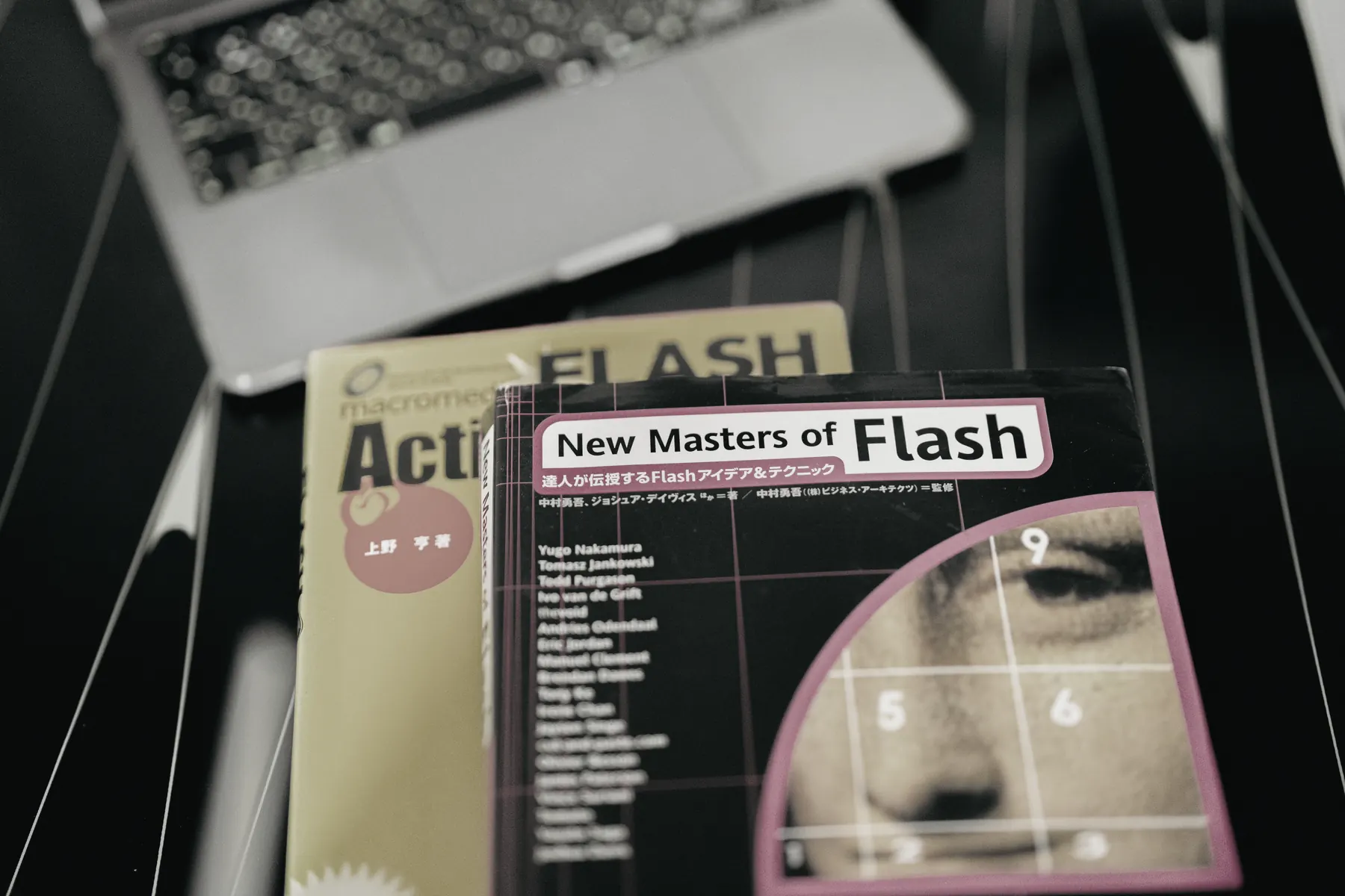 テーブルに置かれたFlashの技術書2冊と、開いたノートパソコン